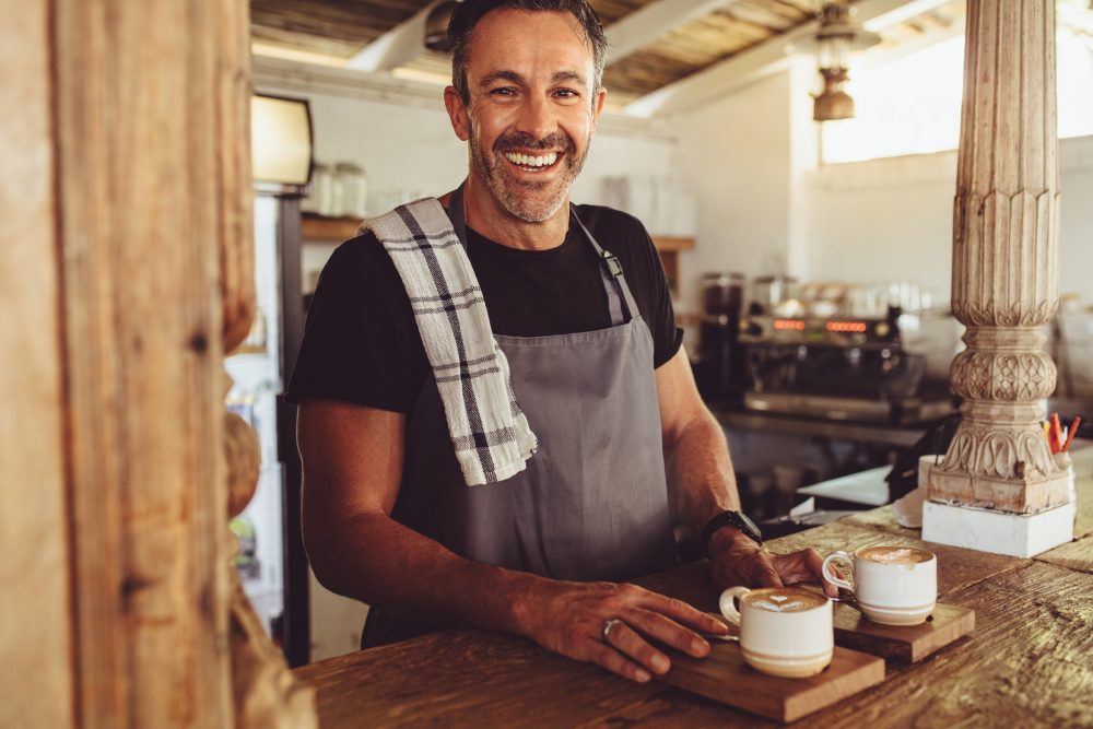 Male barista serving coffee to customers